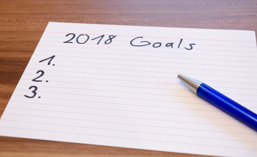 index card with 2018 goals and numbers listed on it, blue pen on top of card