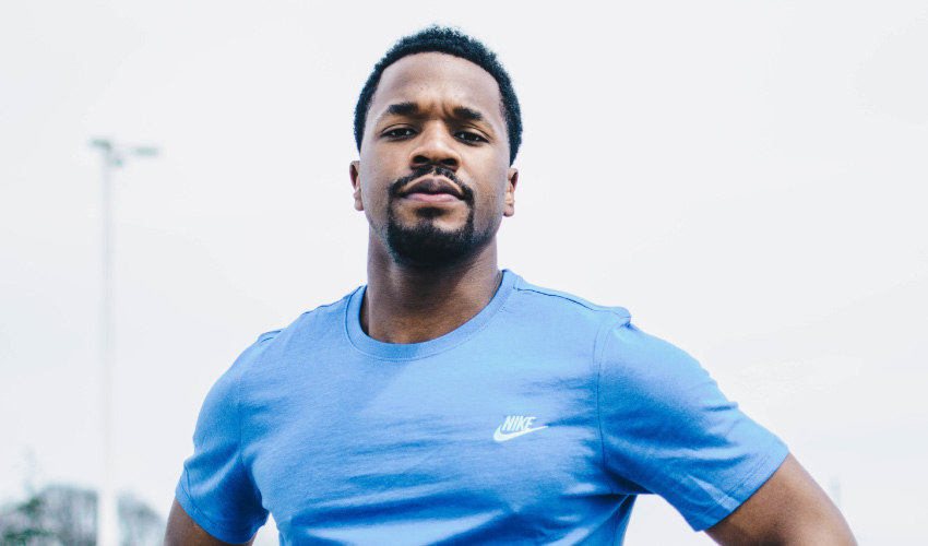 Dark-haired man with a goatee wears a blue shirt with hands on hips wondering if mouthwash is good for teeth 