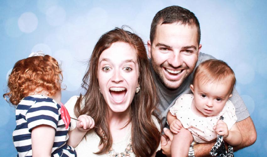 young family of four smiling and laughing