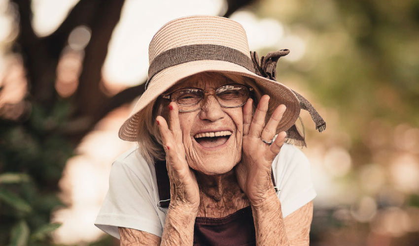 elderly woman wearing a floppy hat calls out