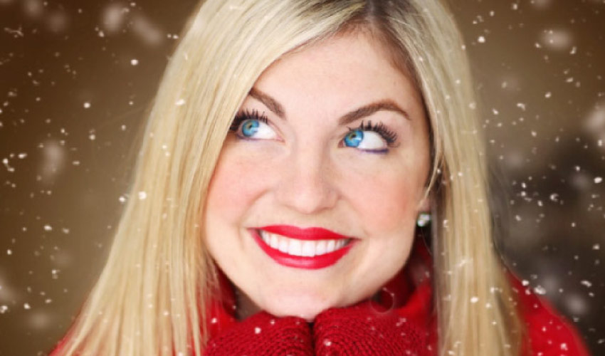 young woman with blond hair, blue eyes, bright red lipstick and sweater smiles after leaving her winter dental appointment