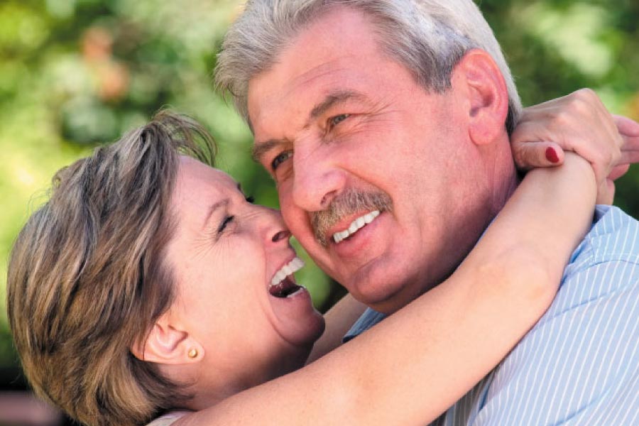 senior couple hug and smile after learning about the benefits of dental implants