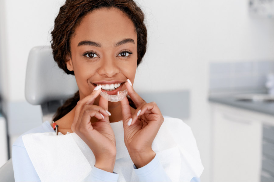 young women gets ready to insert Invisalign clear aligner