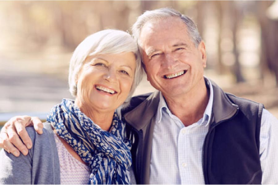 senior couple hug and smile after learning about dental bridges