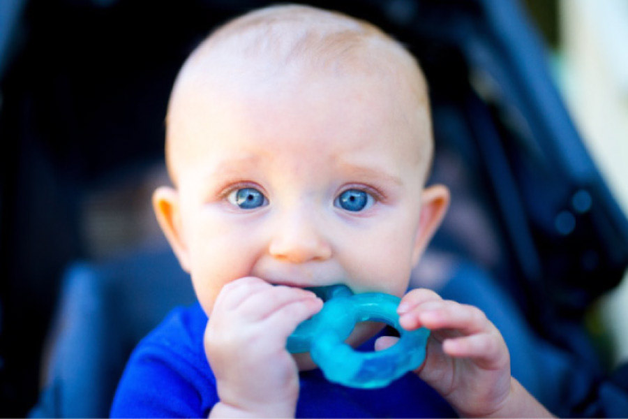 blue eyed baby boy chewing on a teething ring